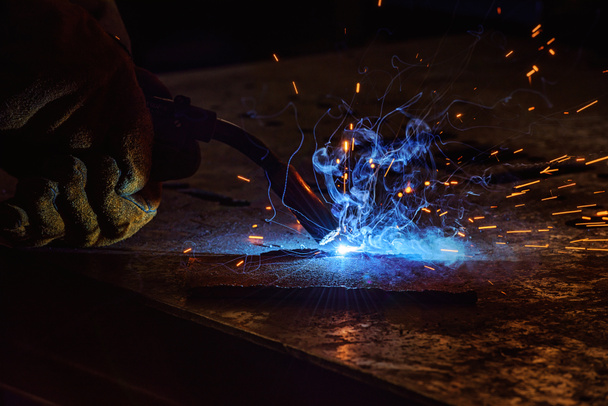 welder brazing metal sparks in a factory